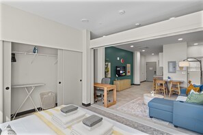 A modern living room with a blue sofa, a wooden dining table, and a kitchen area in the background. - Central Flat: Free Attached Parking | Rooftop |Gym (Kansas City)