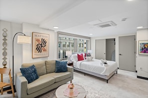 A modern hotel room with a bed, a sofa, a coffee table, and artwork on the walls. - Central Studio: Free Attached Parking |Rooftop|Gym (Kansas City)