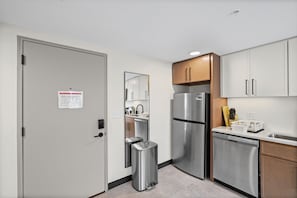 A modern kitchen with stainless steel appliances, wooden cabinets, and a built-in dishwasher. - Central Studio: Free Attached Parking |Rooftop|Gym (Kansas City)