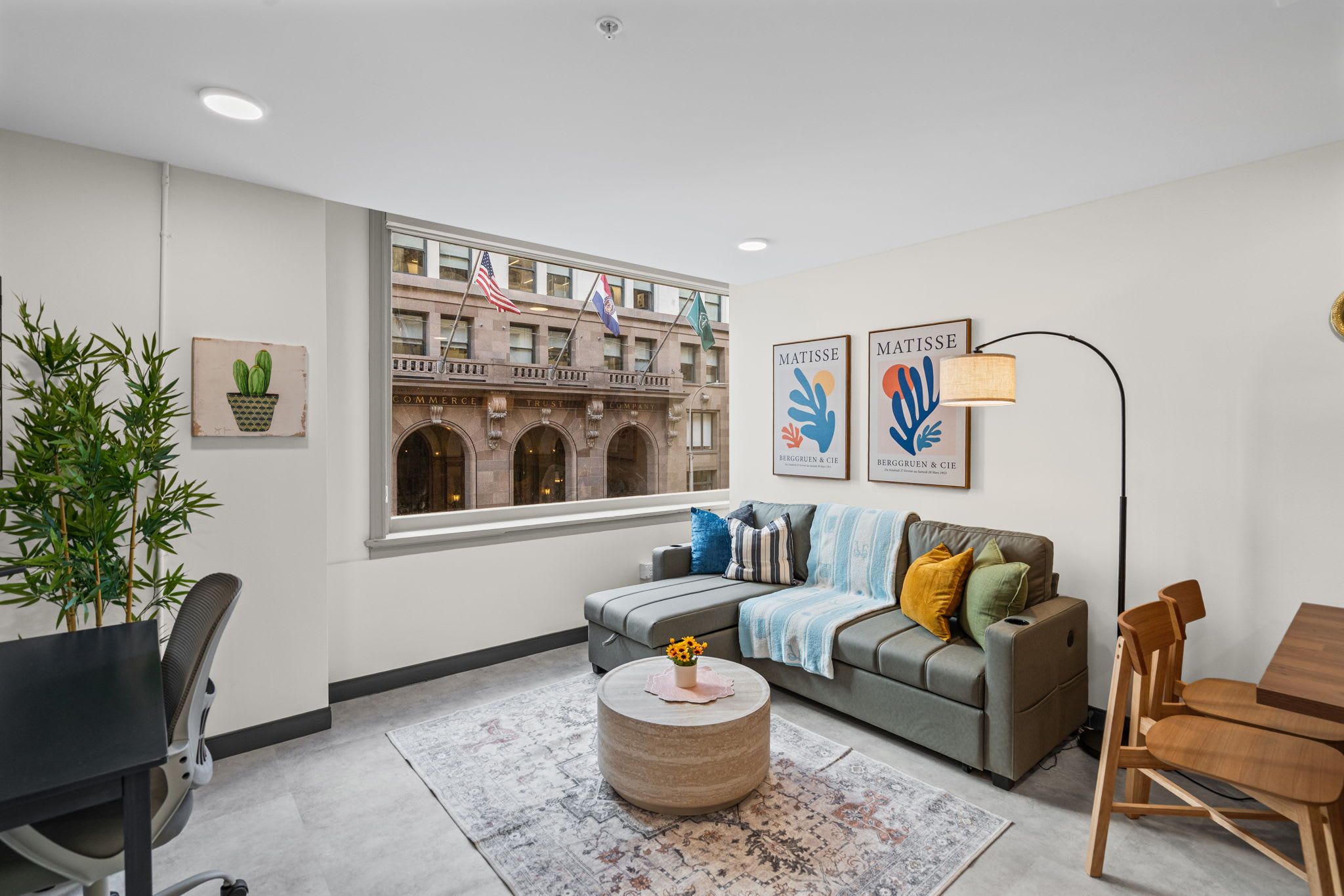 A modern living room with a sofa, coffee table, and a view of a historic building with flags.