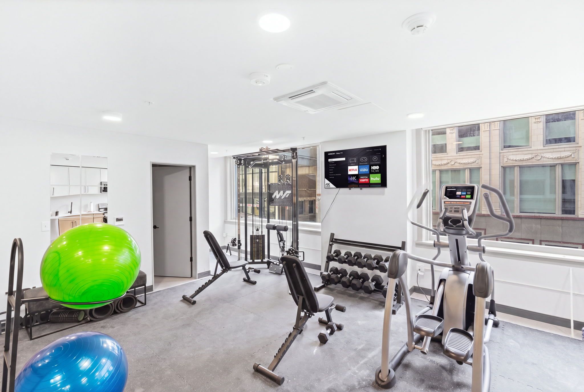 A modern gym with cardio equipment, weight machines, and exercise balls.