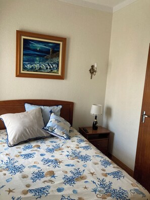 Ein Hotelzimmer mit einem Bett, einem Nachttisch, einer Lampe, einem Gemälde und einer Tür.