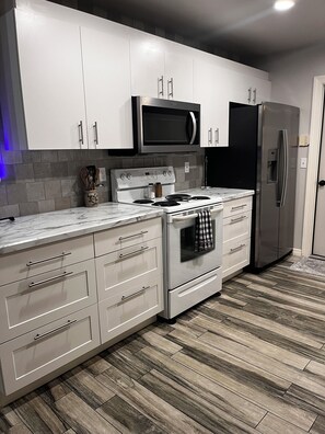 A modern kitchen with white cabinetry, a stainless steel refrigerator, and a built-in microwave above the stove. - Peaceful Palms at Bonita Springs. 10 minutes to the beach and Downtown Shopping (Bonita Springs)