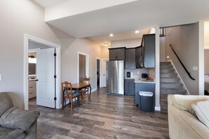 A modern kitchen with dark cabinets, a stainless steel refrigerator, and a dining area with a wooden table and chairs. - Water Toys, Reunion LOZ, Hot Tub, Dock with boat slips (Linn Creek)