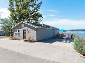 A single-story building with a garage, a covered outdoor seating area, and a view of a body of water. - Water Toys, Reunion LOZ, Hot Tub, Dock with boat slips (Linn Creek)