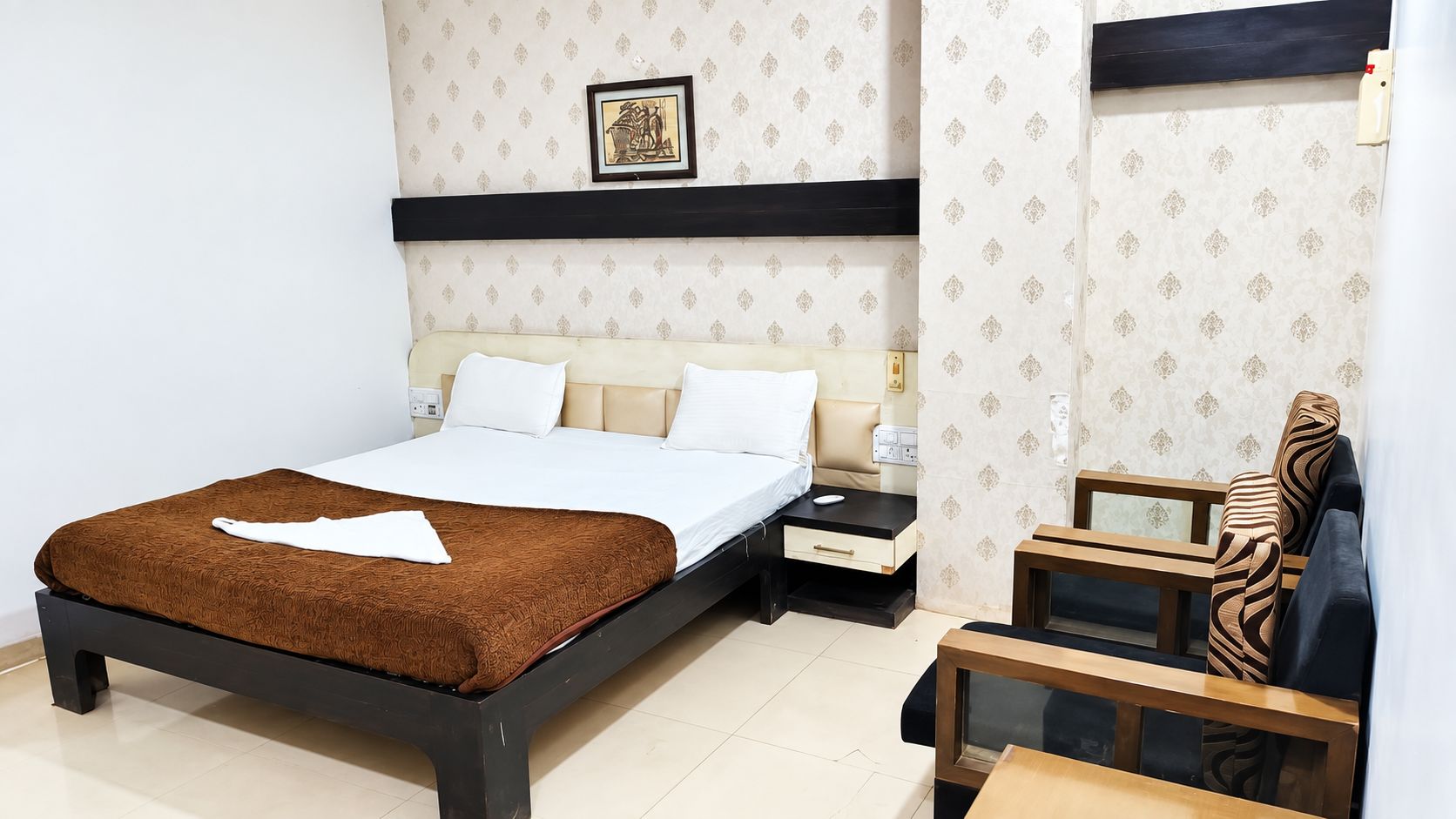 A bedroom with a bed, bedside tables, a nightstand, and a chair.