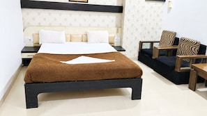 Una habitación de hotel con cama, mesitas de noche, un banco de madera y una pequeña mesa.