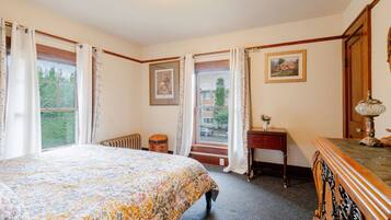 A bedroom with a bed, a dresser, a lamp, and a window with curtains.