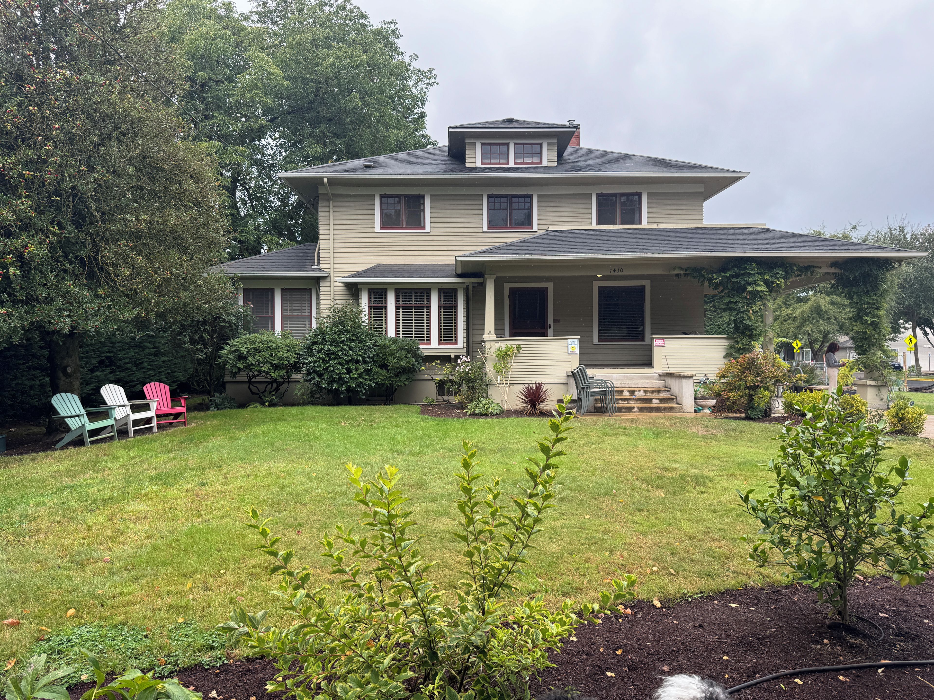 A two-story house with a front porch, a lawn, and outdoor seating.