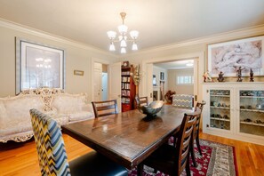 Une salle à manger avec une table en bois, des chaises, un canapé et une bibliothèque.