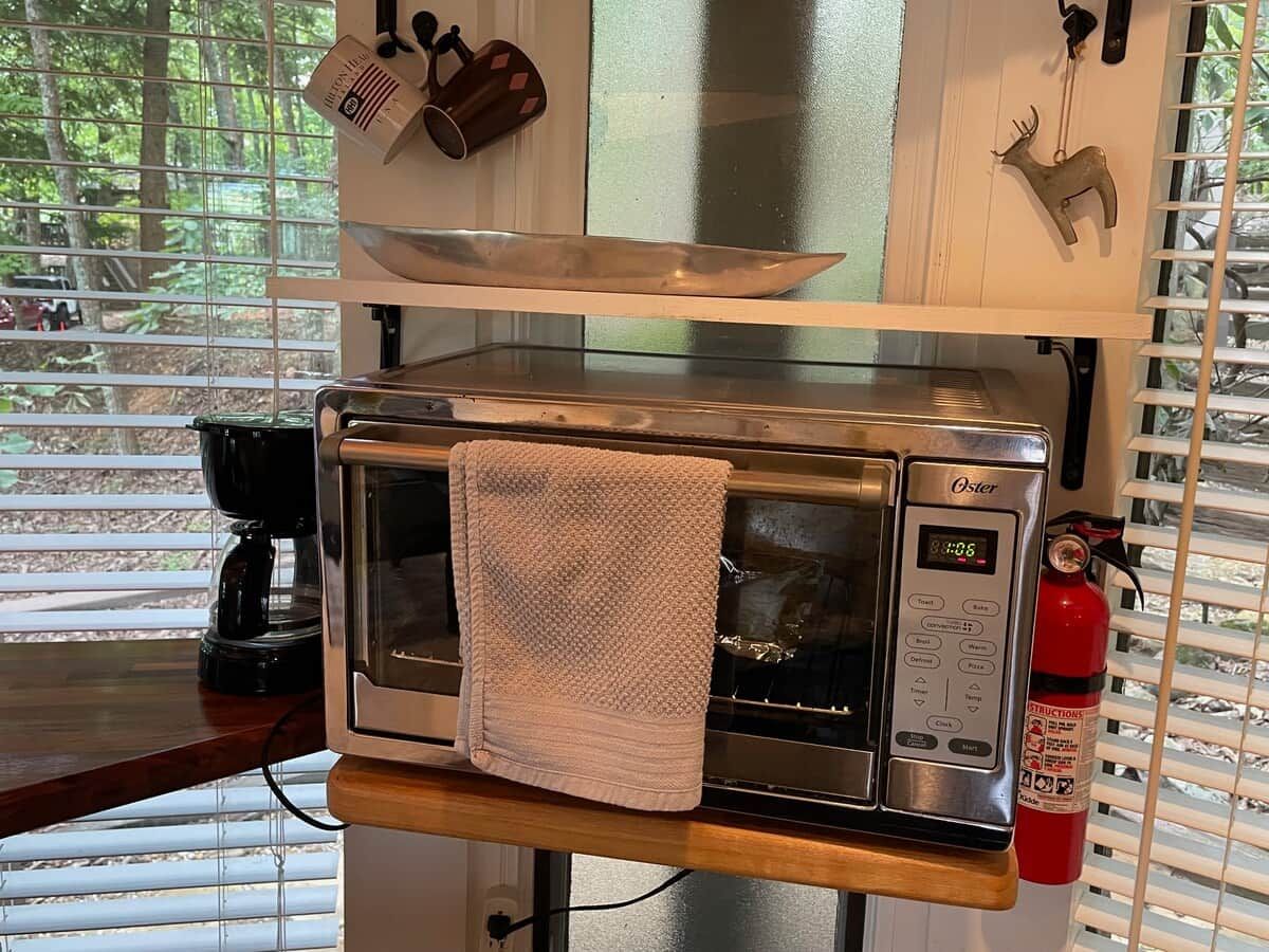 Una cocina con horno tostador Oster incorporado, cafetera y extintor.