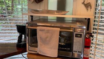 Una cocina con horno tostador Oster incorporado, cafetera y extintor.