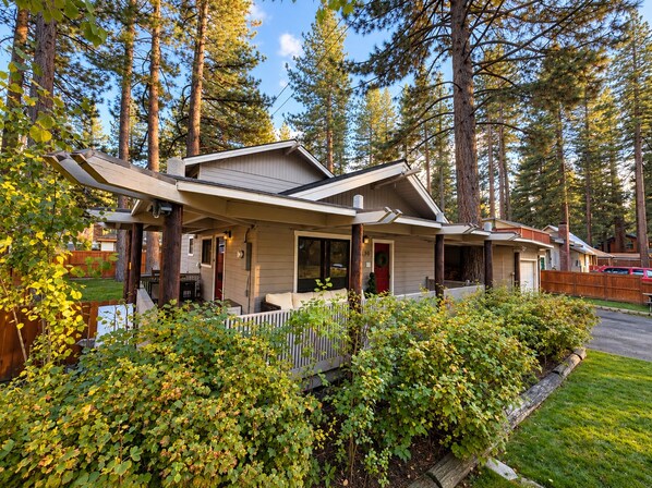 A single-story house with a porch, surrounded by a wooden fence and dense foliage. - Peaceful 4-bedroom house in South Lake Tahoe perfect for families (South Lake Tahoe)