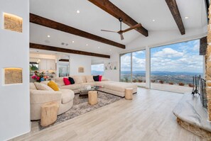 A spacious living room with a large sectional sofa, a coffee table, and a stone fireplace. - Luxe Private Hilltop Escape Pool & Spa 360-views (Valley Center)