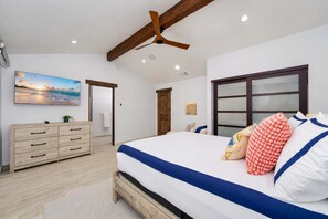 A bedroom with a bed, wooden dresser, and a painting of a beach scene. - Luxe Private Hilltop Escape Pool & Spa 360-views (Valley Center)