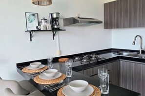 A modern kitchen with a black countertop, stainless steel appliances, and a built-in sink. - 🌊 Oceanfront in Nuevo Vallarta | Infinity Pool (Nuevo Nayarit)