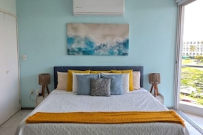 A bedroom with a bed, a painting, and a window with a view. - 🌊 Oceanfront in Nuevo Vallarta | Infinity Pool (Nuevo Nayarit)