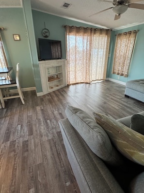 Ein Wohnzimmer mit einer Couch, einem Fernseher auf einem Schrank und einem Deckenventilator.