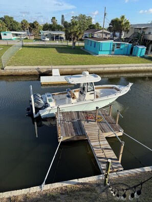 A boat docked at a wooden pier with a Yamaha outboard motor, surrounded by a grassy area with houses and a small dock. - Waterfront Snowbird Retreat with a  Private Dock & Gulf Access (Hudson)