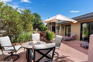 A patio with a round table, two chairs, a fire pit, and an umbrella. - Luxury Red Rock Retreat:  3 Bed/ 2 Bath With Heated Pool & Spa, Game Room (Sedona)