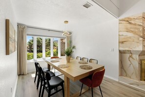A dining area with a wooden table, black and red chairs, a potted plant, and a view through large windows. - Luxury Red Rock Retreat:  3 Bed/ 2 Bath With Heated Pool & Spa, Game Room (Sedona)