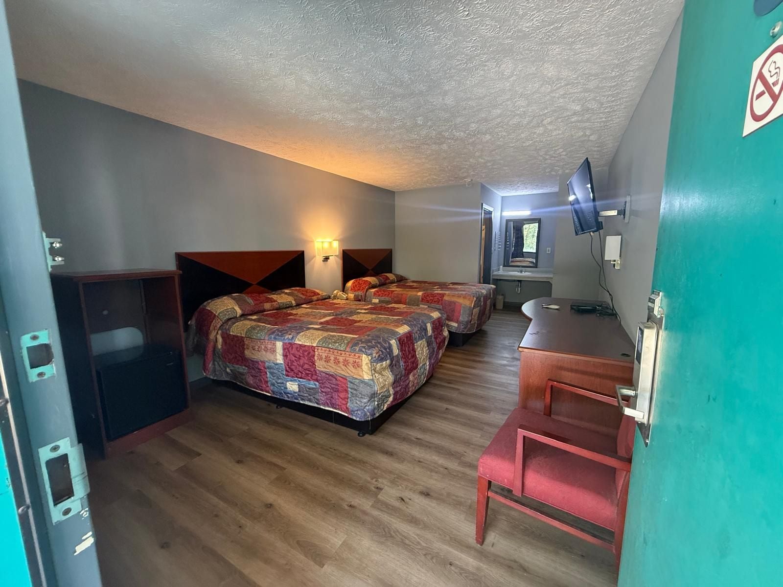 Habitación de hotel con dos camas, un escritorio, un espejo y un televisor.