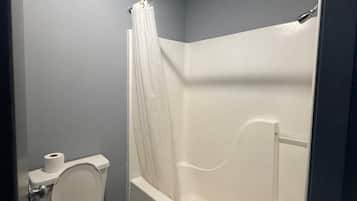 Un baño con inodoro, bañera y cortina de ducha.