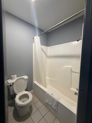 Un baño con inodoro, bañera y cortina de ducha.