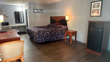 Habitación de hotel con cama, mesita de noche, lámpara, escritorio, silla y armario.