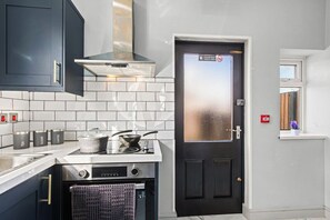 Une cuisine compacte équipée d’une cuisinière, d’un four et d’une porte noire avec un panneau en verre dépoli.