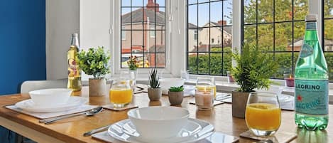 A breakfast table set with white dishes, glasses, and a bottle of mineral water.