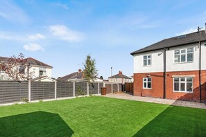 A residential property with a well-maintained lawn, a brick house, and a wooden fence. - 4 Doubles, 4 En-Suites & a Big Garden – Sleeps 8 (Ashton-on-Ribble)