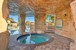 A spa area with a hot tub, stone pillars, a pool, and a sign with spa rules. - Family 4br, Private Pool, Resort Amenities (Kissimmee)