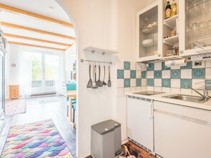 A kitchen with white cabinets, a sink, and a window overlooking a deck. - Apartment Stephi by Interhome (Neukirchen beim Heiligen Blut)