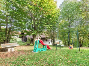 Ein Spielplatz mit Rutsche, Schaukeln und einer Sitzbank.
