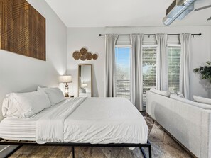 A hotel room with a bed, a sofa, a mirror, and a window with curtains. - 1BR,FREE Parking.Near AAC, 182 (Dallas)