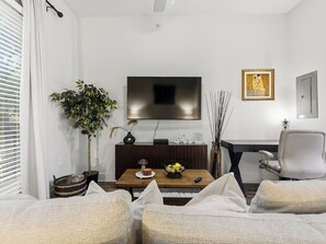 A modern living room with a flat-screen TV, a wooden coffee table, a comfortable sofa, a side table, and a potted plant. - 1BR,FREE Parking.Near AAC, 182 (Dallas)