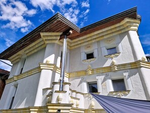 Ein Gebäude mit weißer Fassade, einem Holzdach und blauem Himmel im Hintergrund.