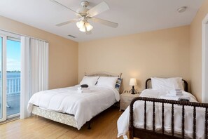 Quarto de hotel com duas camas, um ventilador de teto e vista para a água.