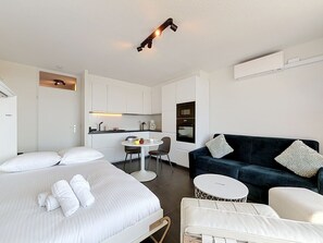 A hotel room with a bed, a sofa, a small dining table, and a kitchenette. - Astrid with parking and seaview by Interhome (Bredene)
