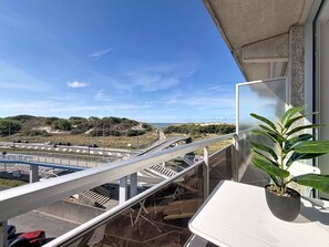A balcony with a view of a road, a pedestrian bridge, and a distant landscape. - Astrid with parking and seaview by Interhome (Bredene)
