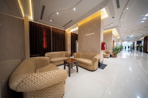 A hotel lobby with sofas, a coffee table, and a fire extinguisher. - multazam Hotel (Makkah)