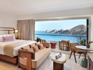 A modern bedroom with a large bed, a sofa, a dining table, and a view of the sea. - corazone cabo  3-bedroom condo with jacuzzi in superb Cabo San Lucas (Cabo San Lucas)