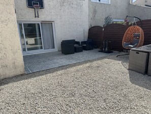 A patio area with a basketball hoop, outdoor seating, and a wicker table. - Elegant house with a garden, terraces, and parking on the outskirts of Fontainebleau (Saint-Pierre-lès-Nemours)