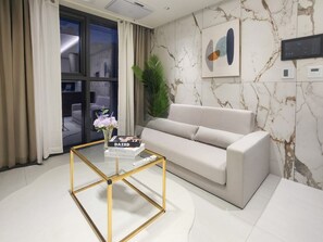 Ein modernes Wohnzimmer mit einer Couch, einem Glastisch und einem Blumentopf.