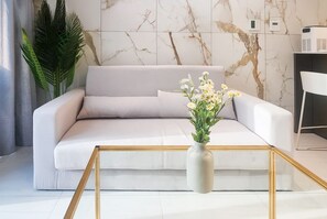 Ein modernes Wohnzimmer mit einem weißen Sofa, einem Glastisch und einer Blumenvase.