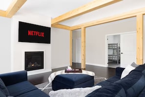 A living room with a fireplace, a couch, a coffee table, and a TV mounted on the wall. - 20 Mins to Arrowhead Family Friendly Getaway (Huntsville)