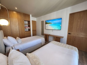 Quarto de hotel com duas camas, televisão e painéis de madeira.