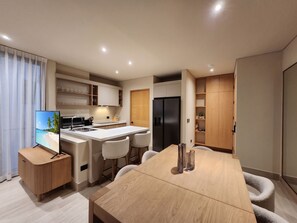 Eine moderne Küche mit einer zentralen Kochinsel, integrierten Geräten und einem Essbereich mit Holztisch und Stühlen.