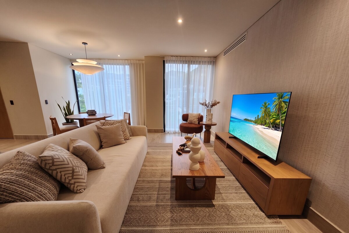 Ein modernes Wohnzimmer mit einer Couch, einem Couchtisch und einem Flachbildfernseher auf einem Holzboden.